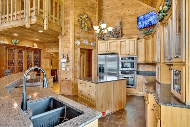 kitchen with sink, a kitchen island, wooden walls, and appliances with stainless steel finishes