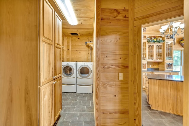 clothes washing area featuring wooden walls, washer and clothes dryer, a chandelier, and wooden ceiling