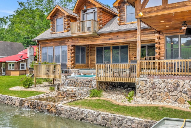 back of property with a balcony and a water view