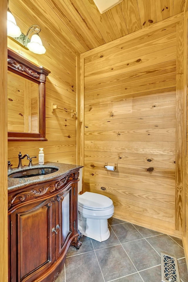 bathroom with wooden walls, wooden ceiling, toilet, tile patterned floors, and vanity