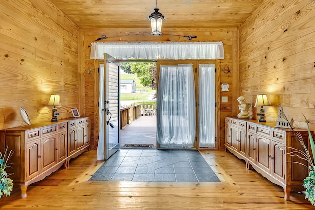 doorway featuring light hardwood / wood-style flooring, wooden walls, and wooden ceiling