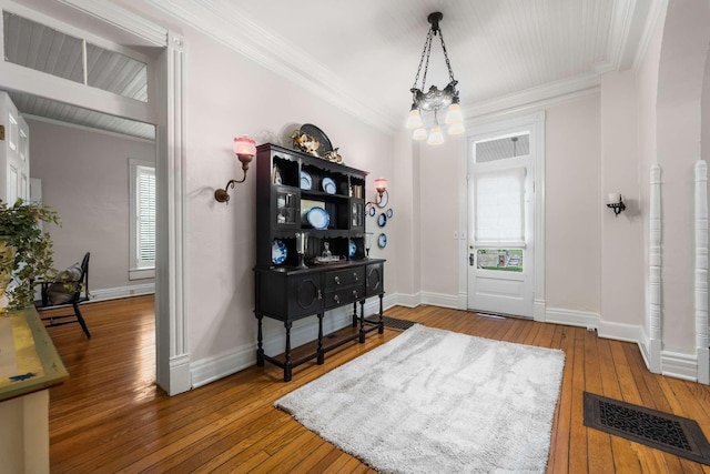 entryway with hardwood / wood-style flooring, ornamental molding, and a chandelier