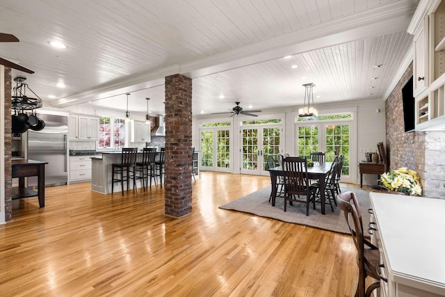 dining room with beamed ceiling, light hardwood / wood-style floors, decorative columns, and ceiling fan