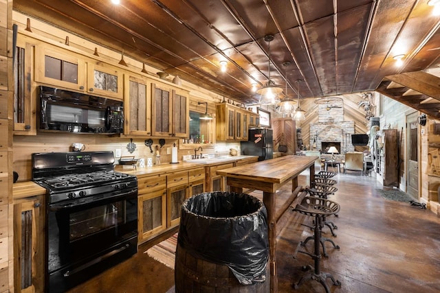 kitchen featuring sink, butcher block countertops, wood ceiling, wooden walls, and black appliances