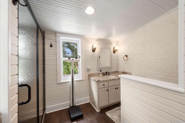 bathroom with hardwood / wood-style flooring, vanity, and a shower with door