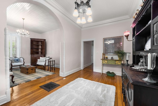 interior space featuring hardwood / wood-style flooring, crown molding, and a notable chandelier