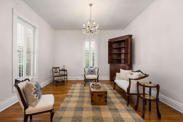 living area featuring hardwood / wood-style flooring, crown molding, and an inviting chandelier