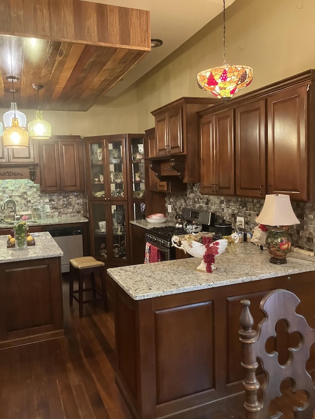 kitchen featuring light stone countertops, dark wood-type flooring, hanging light fixtures, stainless steel appliances, and decorative backsplash