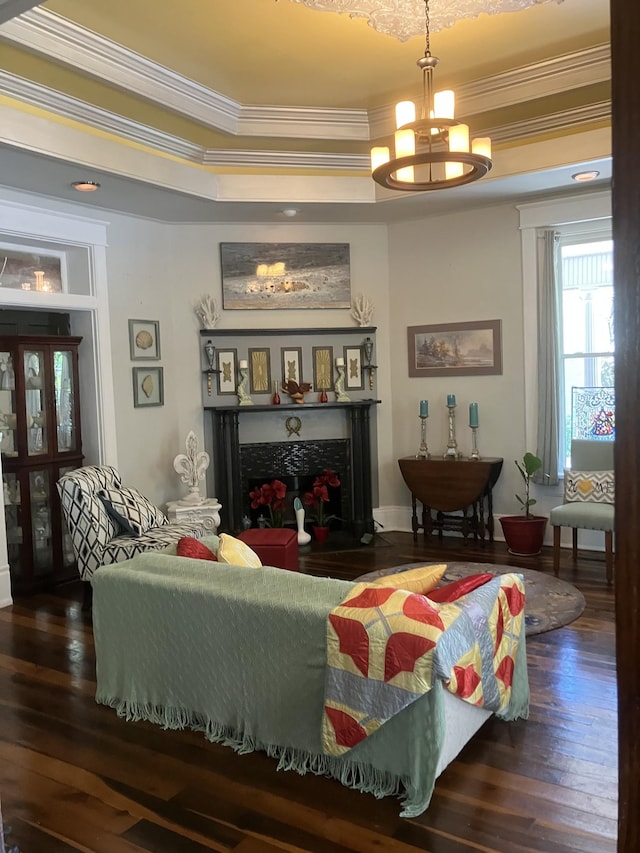 living room with a chandelier, a tray ceiling, dark hardwood / wood-style floors, and ornamental molding