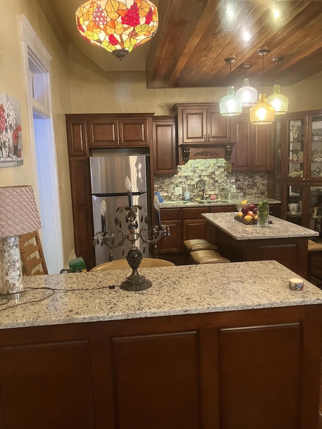 kitchen with stainless steel refrigerator, a center island, backsplash, decorative light fixtures, and wood ceiling