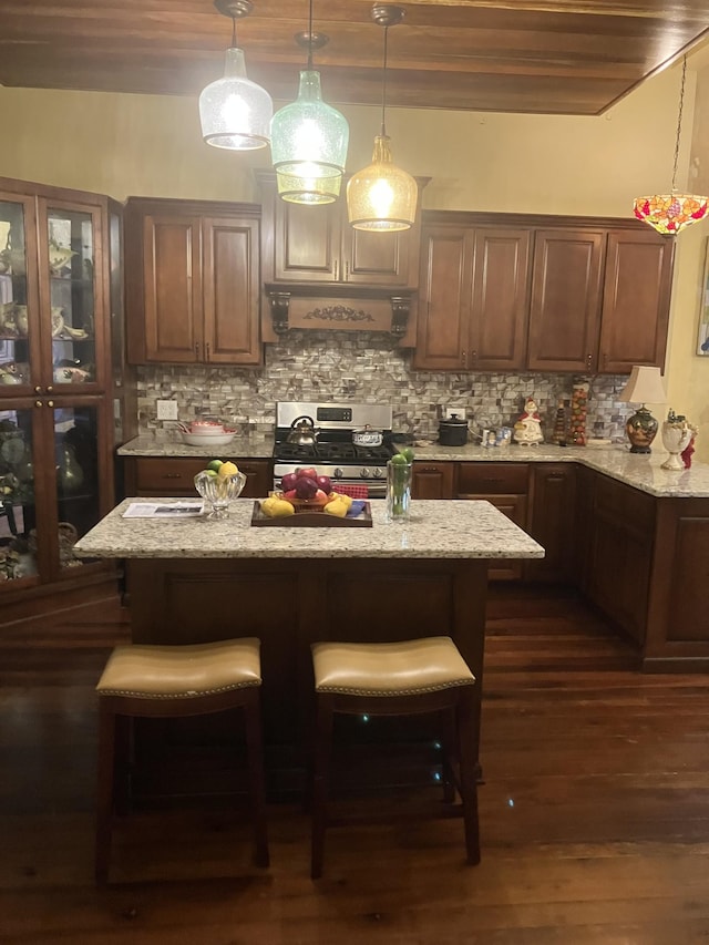 kitchen featuring stainless steel range oven, light stone countertops, backsplash, and dark wood-type flooring