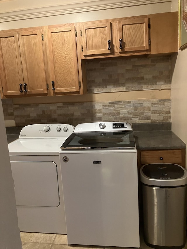 washroom with separate washer and dryer, light tile patterned floors, and cabinets