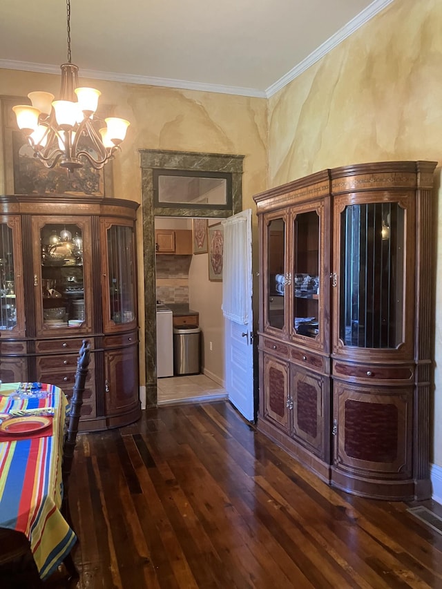 unfurnished dining area with crown molding, dark hardwood / wood-style flooring, a chandelier, and independent washer and dryer