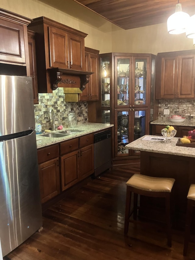 kitchen featuring dark wood-type flooring, hanging light fixtures, light stone countertops, tasteful backsplash, and stainless steel appliances