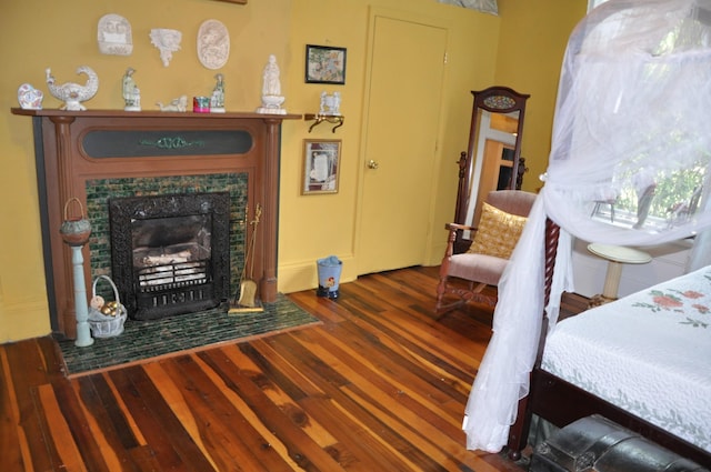 bedroom featuring a tiled fireplace and dark wood-type flooring