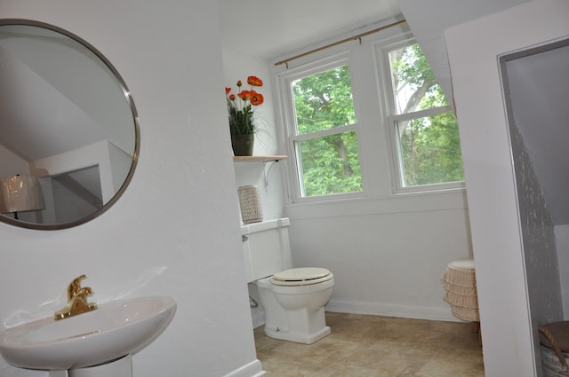 bathroom with a sink, toilet, and baseboards