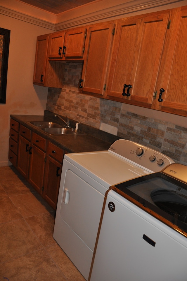 clothes washing area featuring cabinets, light tile patterned floors, sink, and washing machine and clothes dryer