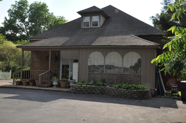 view of front of property featuring brick siding and a shingled roof