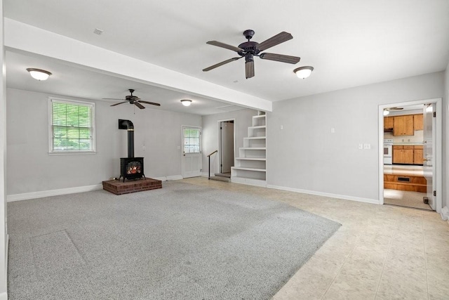 unfurnished living room with a wood stove and ceiling fan