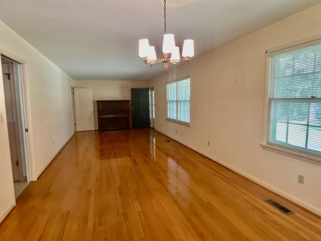 unfurnished dining area with an inviting chandelier and light hardwood / wood-style floors