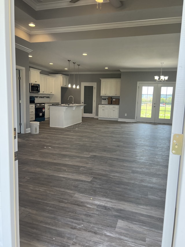 unfurnished living room featuring dark wood-type flooring, ceiling fan with notable chandelier, crown molding, and sink