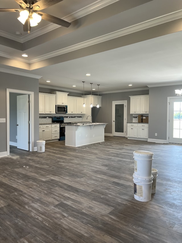 kitchen with ceiling fan with notable chandelier, appliances with stainless steel finishes, white cabinetry, a center island with sink, and ornamental molding