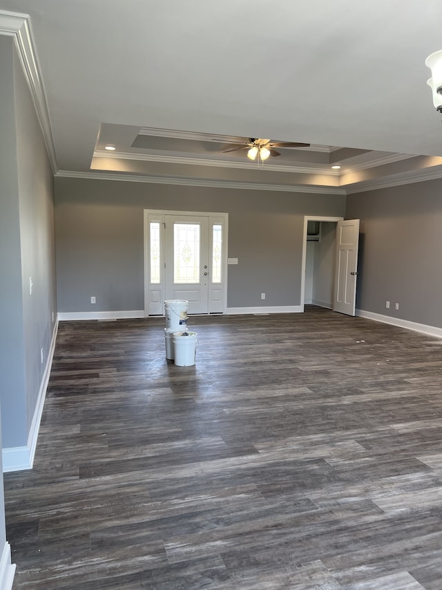 empty room with dark hardwood / wood-style flooring, ceiling fan, a raised ceiling, and crown molding