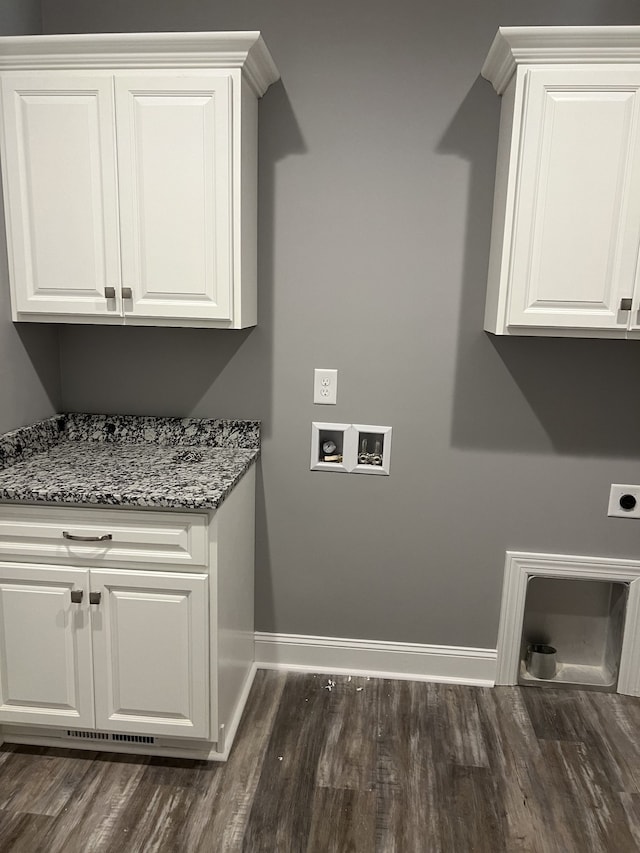 clothes washing area with dark wood-type flooring, electric dryer hookup, washer hookup, and cabinets