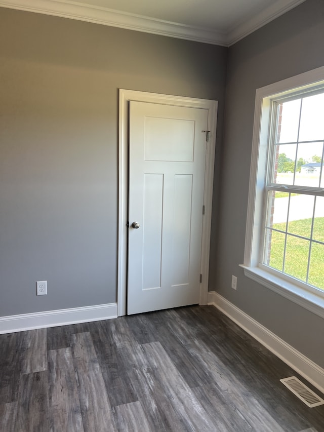 empty room with dark hardwood / wood-style flooring and ornamental molding