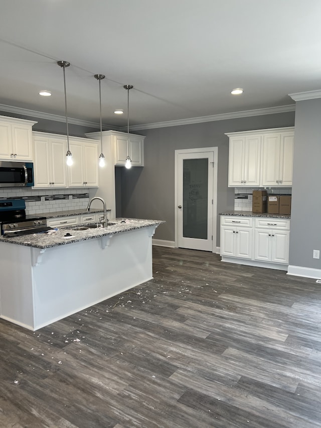 kitchen with dark stone counters, decorative light fixtures, stainless steel appliances, sink, and white cabinets