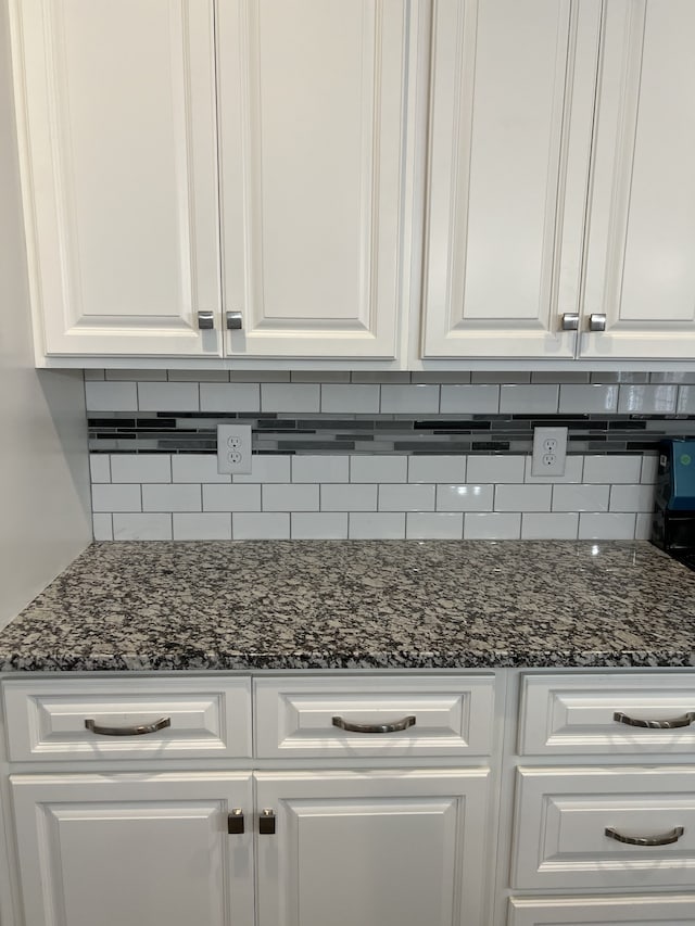 room details featuring dark stone countertops and white cabinets