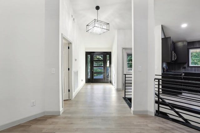 entryway featuring light wood finished floors, baseboards, and an inviting chandelier