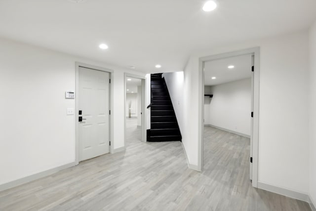 finished below grade area with light wood-type flooring, stairway, and recessed lighting