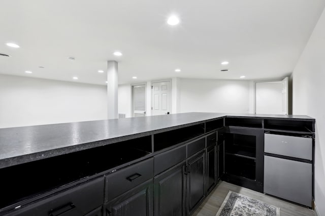 kitchen with light wood finished floors, dark countertops, freestanding refrigerator, dark cabinetry, and recessed lighting