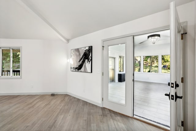 doorway with lofted ceiling, wood finished floors, and baseboards