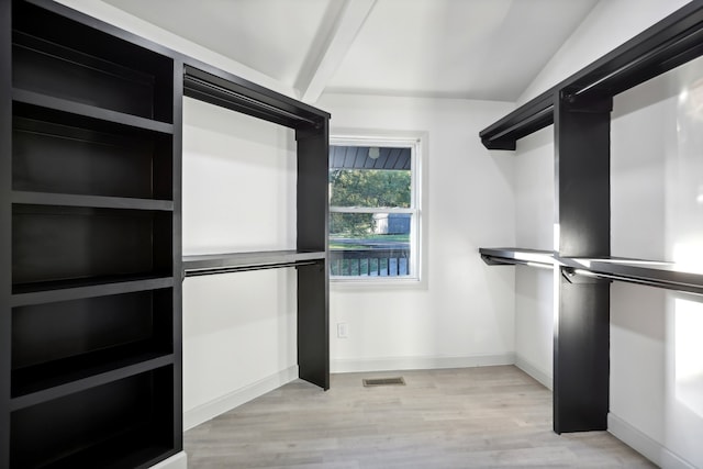 walk in closet featuring lofted ceiling with beams, light wood-style flooring, and visible vents