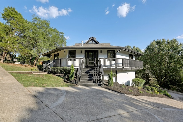 view of front of property with covered porch, a front lawn, and stairs