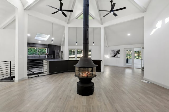 living room featuring a skylight, light wood-style flooring, and beam ceiling