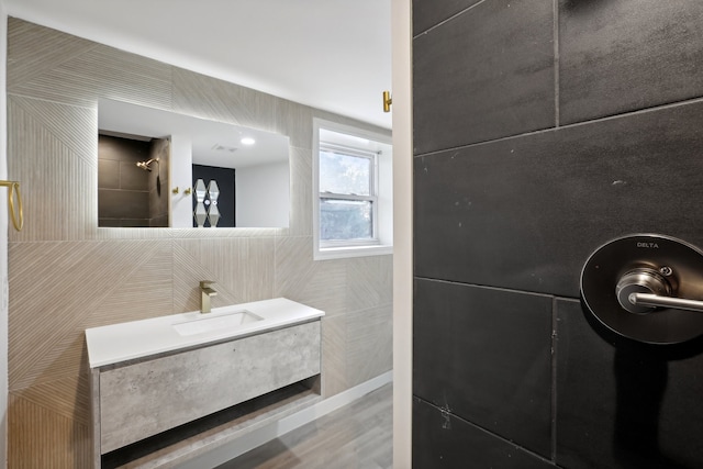 bathroom with vanity, walk in shower, and tile walls