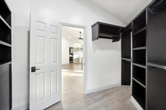 spacious closet featuring lofted ceiling, light wood-style flooring, and ceiling fan