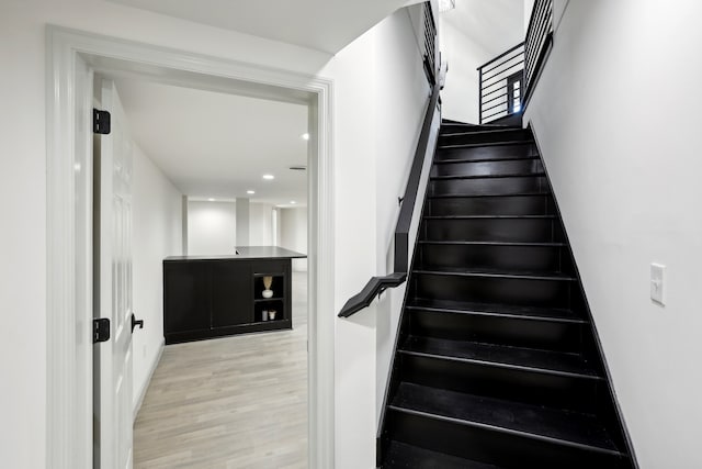 stairs featuring wood finished floors and recessed lighting