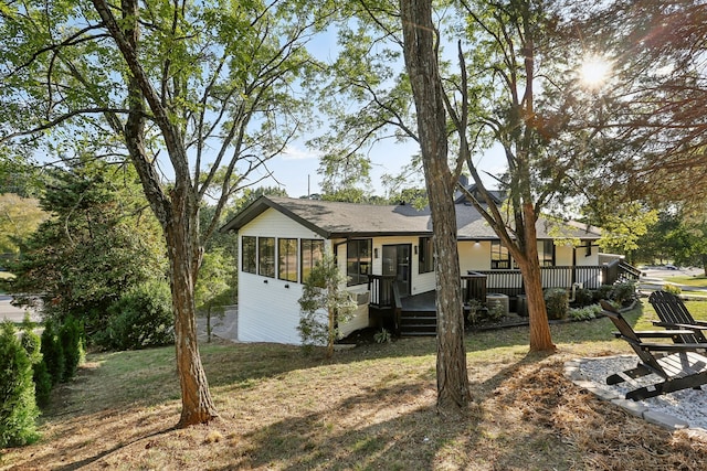 view of front of home featuring a sunroom, a front lawn, and a deck