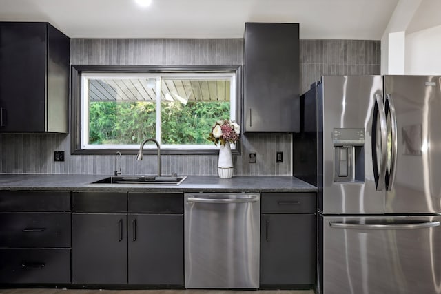 kitchen featuring appliances with stainless steel finishes, dark countertops, a sink, and tasteful backsplash