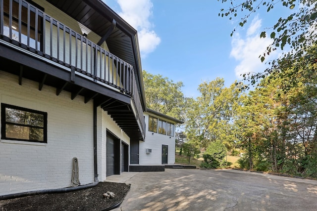 view of patio featuring driveway, a balcony, and an attached garage