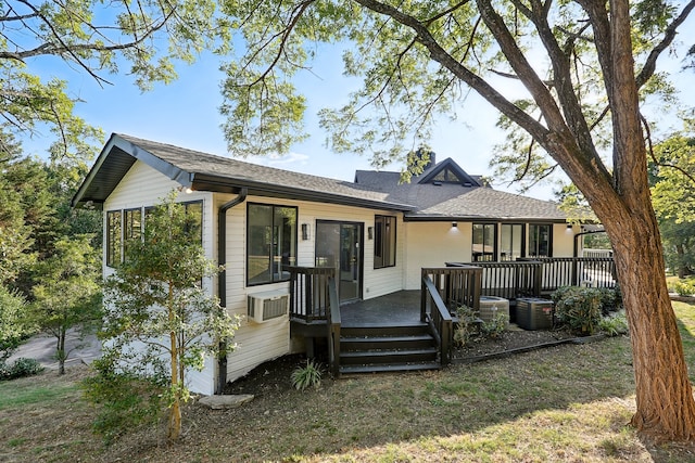 back of house with roof with shingles, a chimney, central AC, a deck, and a wall mounted air conditioner