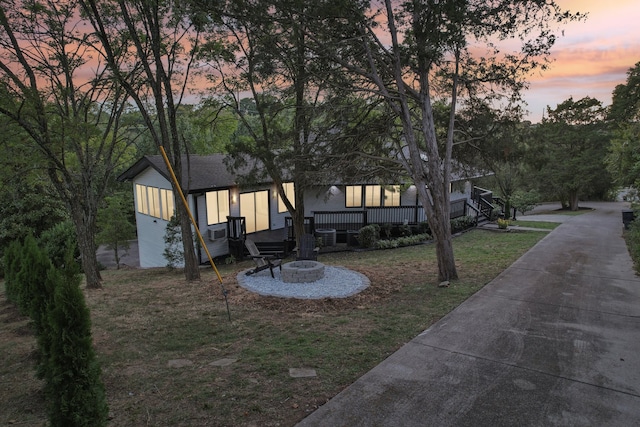 rear view of property featuring a yard, an outdoor fire pit, and a shingled roof