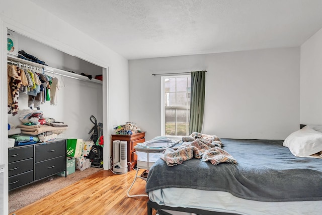 bedroom featuring hardwood / wood-style floors, a textured ceiling, and a closet