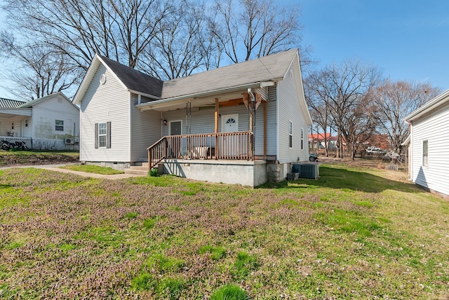 rear view of house with central AC unit and a lawn