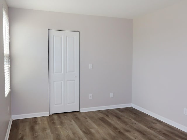 unfurnished bedroom with a closet and dark wood-type flooring