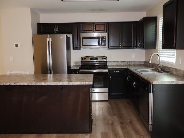 kitchen featuring dark brown cabinetry, sink, appliances with stainless steel finishes, and dark wood-type flooring